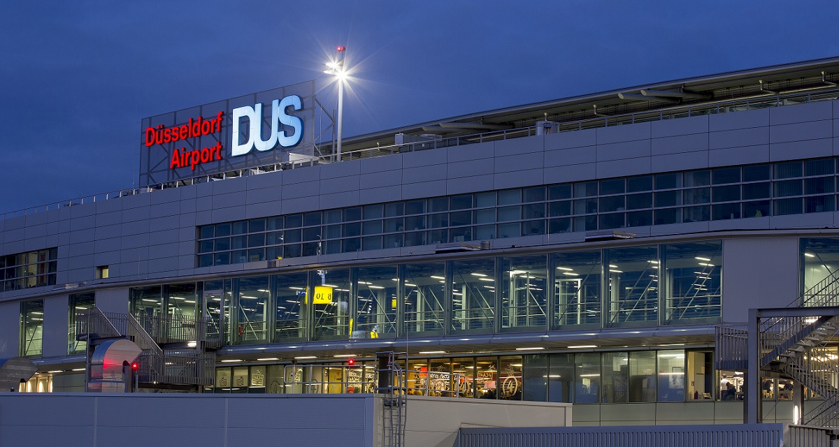 GBMpic_ Außenansicht des Düsseldorfer Flughafenterminals in der Dämmerung mit beleuchteter Beschilderung. GBM Essen, Projektmanagement, Organisationsberatung, VGV Verfahren, Terminplanung, Projektsteuerung